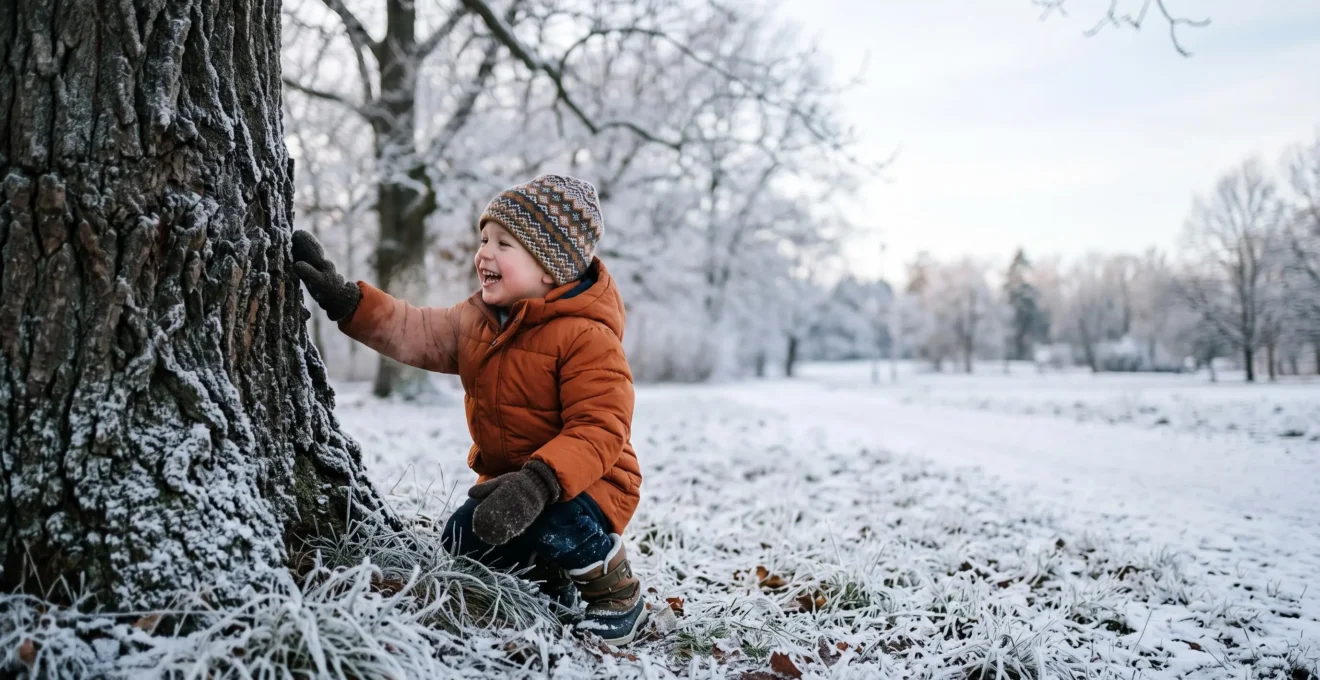 A bundled-up child crouching in a winter park, gently touching the frosty texture of a tree trunk during a sensory scavenger hunt