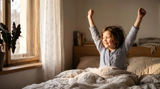 A child stretching and waking up peacefully as warm morning sunlight fills the bedroom, symbolizing a reset circadian rhythm