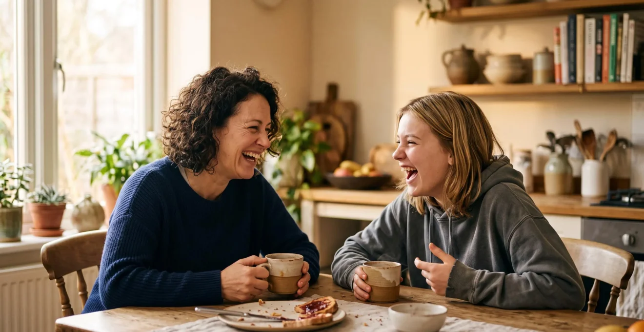 A parent and teenager sharing a relaxed, laughing moment during a weekend morning ritual at a kitchen table bathed in soft light.